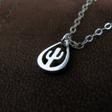 Silver necklace with a cactus pendant on a brown textured background