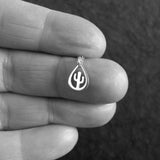Silver teardrop-shaped pendant with a cactus design held between fingers.