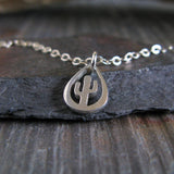 Silver necklace with a cactus pendant on a dark stone surface