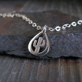 Silver necklace with a cactus pendant on a dark stone surface