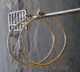 gold hoop earrings hanging in fron of gray stone