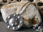 silver and black pendant with dots in front of light rock