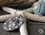 sideview of silver and black pendant necklace on white starfish