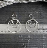 Three circles silver earrings shown on gray stone with a metric ruler
