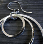 Close up of silver earring with 3 rings and different textures