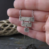 Inverted pyramid silver pendant necklace shown in hand