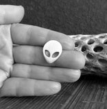 silver alien tie tack pin held in hand with driftwood black and white
