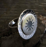 Side view of silver sun ring on dark background
