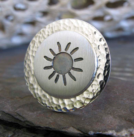 Silver sun disc ring on stone with driftwood