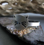 silver cat face ring on rock with driftwood