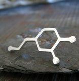 Silver Dopamine Molecule tie tack pin on gray rock