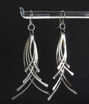 hanging silver earrings on black background