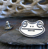 Frog Face silver tie tack on gray stone with driftwood
