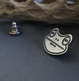 side view of frog pin on black background with driftwood