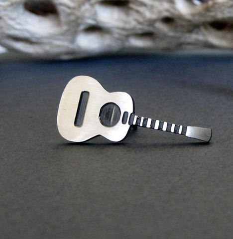 Acoustic Guitar tie tack pin on gray background with driftwood