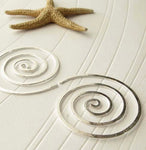 Spiral hoop earrings on white paper with small starfish