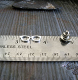 silver glasses pin shown on ruler and gray stone