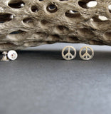 silver peace sign stud earring on gray with driftwood
