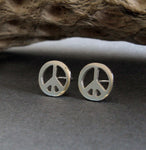 silver peace sign stud earring on gray with driftwood