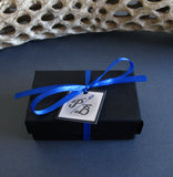 black cardboard jewelry box with blue ribbon and white tag PB