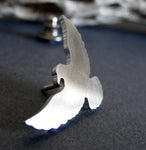 side view of silver raven pin withopen wings on dark background