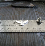 flying raven silver pin shown on ruler and gray stone