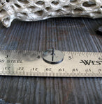 round black tie tack on a ruler with driftwood background