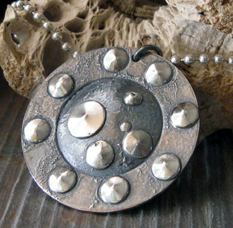 gunmetal and silver dot pendant necklace on gray stone with driftwood
