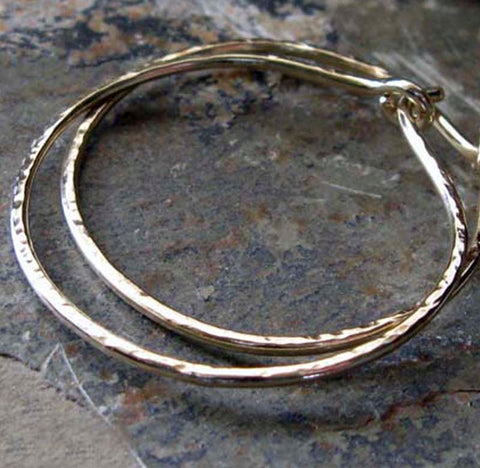 Hammered gold hoop earrings on gray rock