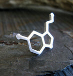 silver serotonin molecule tie tack on rock