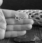 Serotonin molecule tie tack held in hand with driftwood
