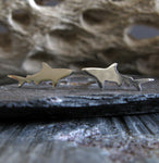 sterling silver shark earrings on gray stone with driftwood