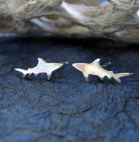 Silver Shark stud earrings on dark blue background with driftwood