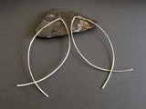 silver wire fish earrings on gray background with rock