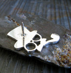 Back of steampunk silver lapel pin on gray rock