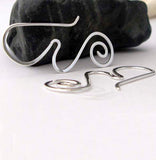 Silver wave and spiral earrings on white background with black rock