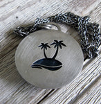 Palm Trees cut out on back of sterling silver pendant on wood grain