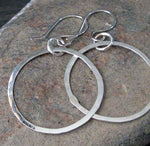 Silver dangle hoop earrings on gray rock