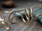 Gold spiral wire earrings on gray stone
