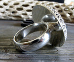Reverse side of sterling silver ring on gray stone with tree branch