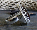Side view of sterling silver gemstone ring on gray with tree branch