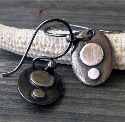 silver and black oval earrings on gray stone with white starfish