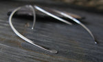 Silver spike wire earrings on gray tile