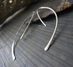 Silver spike wire earrings on gray stone with rock