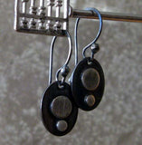 silver dot oval earrings hanging from abacus in front of gray stone