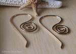 gold spiral wire earrings on tan wood with starfish