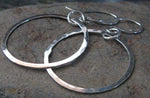 Silver dangle hoop earrings on gray rock