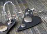 Gunmetal heart earrings with silver dots on gray stone tile