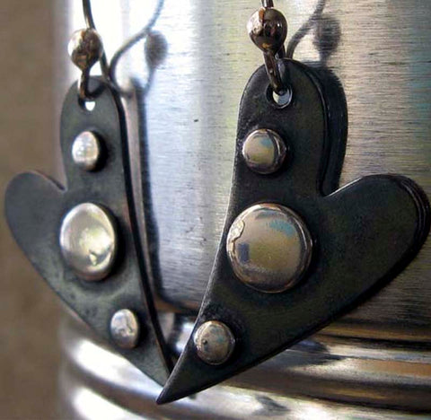 black heart with silver dot earrings in front of tin can