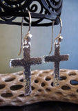 hanging silver cross earrings with driftwood and light blue background